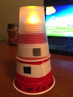 a red and white light on top of a wooden table next to a laptop computer