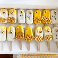 there are many yellow and white pops with bees on them in a box next to a table