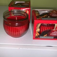 a red candle sitting on top of a white counter next to boxes of cookies and other items