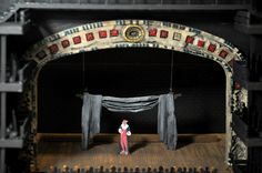 a man standing on top of a stage in front of an arch with curtains over it