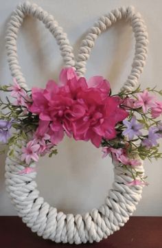 a white rope wreath with pink and purple flowers