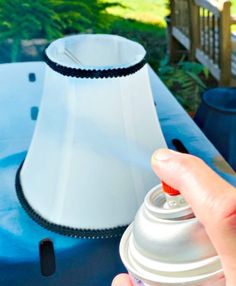 a person is holding a spray bottle in front of a lamp on a blue table