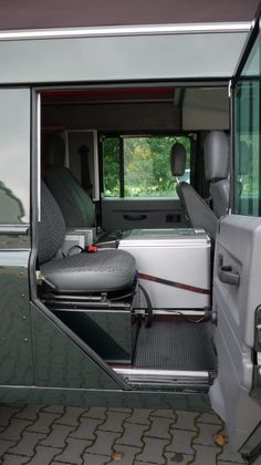 the interior of a vehicle with its door open and seats in place for people to sit