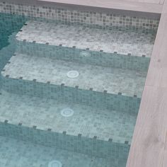 an empty swimming pool with tiled steps leading up to the water's edge,