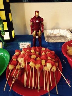 a table topped with watermelon skewers and iron man figurines