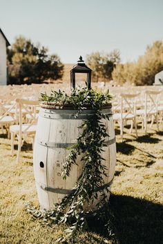 an old barrel with greenery on it is surrounded by rows of chairs