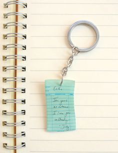 a note pad with a keychain attached to it sitting on top of a notebook