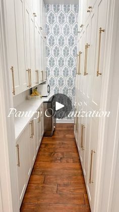 a narrow kitchen with white cabinets and wood floors