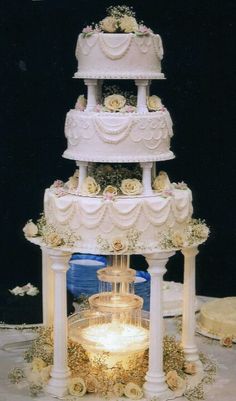 a three tiered wedding cake with roses on the top and bottom, sitting on a table