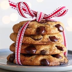 a stack of chocolate chip cookies tied with a red and white ribbon on a plate