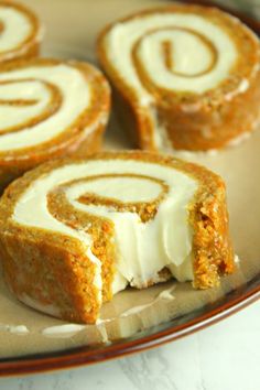 three cinnamon rolls on a plate with one cut in half and the other partially eaten