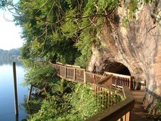 a wooden walkway leading to a cave next to the water