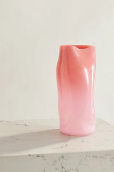 a pink vase sitting on top of a white counter next to a marble slaby surface