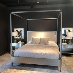 a bed with white sheets and pillows in a room that has black walls, two lamps on either side of the bed