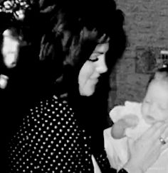 a woman holding a baby in her arms while another woman holds the child up to her chest