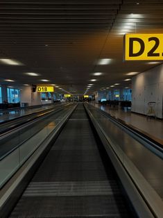 an empty train station with no people on the escalator and signs above it