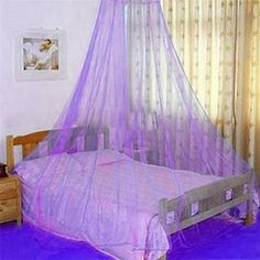 a bed with a purple canopy over it in a room next to a dresser and window