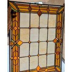 an old stained glass window with yellow and white squares on the bottom, surrounded by brown trim