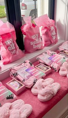 pink items are displayed on a table in front of a window with bags behind them