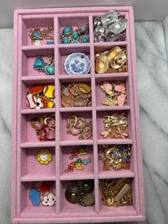 a pink jewelry box filled with lots of different types of brooches and earrings