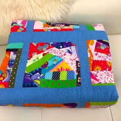 a colorful patchwork pillow on a white couch with a furnishing behind it