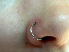 a close up of a person's nose with an open nose ring on it