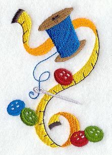 a spool of thread and some balls of yarn on a white tablecloth with an image of a snake