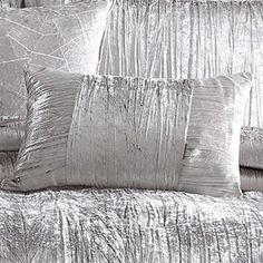 a bed with silver sheets and pillows on it