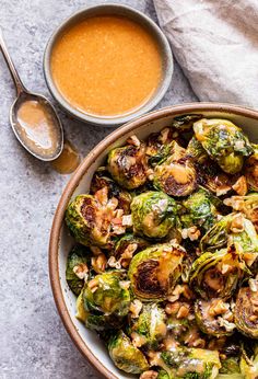 a bowl filled with brussel sprouts and nuts next to a spoon