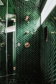 a green tiled bathroom with gold fixtures and glass shower door, all in the same color