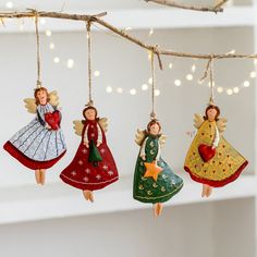 three christmas ornaments hanging from a branch with string lights in the background and fairy lights strung above them