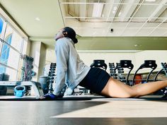 a woman laying on the floor in a gym with her legs crossed and looking up