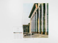 an open book with columns and people walking by it on a white surface next to a wall