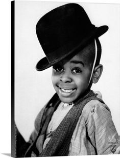 a black and white photo of a young boy wearing a hat