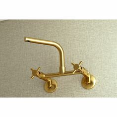 a gold faucet mounted to the side of a wall with two wheels on it