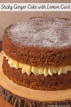 a close up of a cake with icing on a wooden platter and text overlay that reads sticky ginger cake with lemon curd