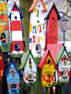 many colorful bird houses are hanging from a tree