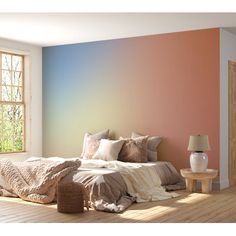 a bedroom with a large bed in front of a colorful wall and wooden flooring