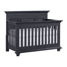 a black crib with white sheets on it