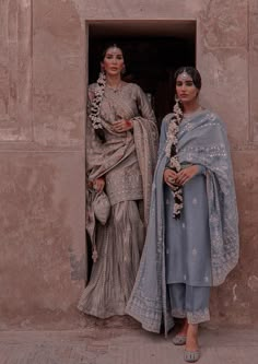 two women standing next to each other in front of a doorway