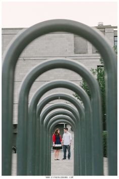 two people walking down a walkway lined with metal tubes