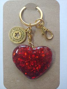 a red heart shaped keychain with a gold plated charm attached to it