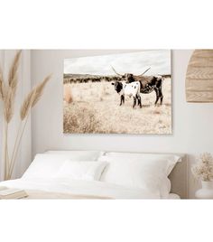 two cows standing in the grass near each other on a bed with white sheets and pillows