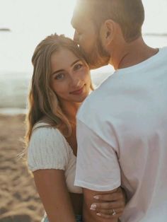 a man and woman standing next to each other at the beach with sun shining on them