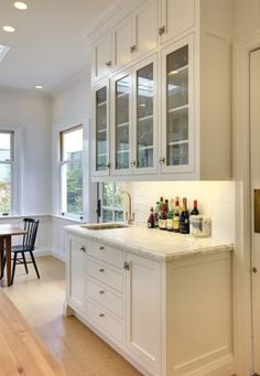 a kitchen with white cabinets and marble counter tops