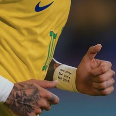 a man with tattoos on his arm wearing a yellow shirt and pointing to the side