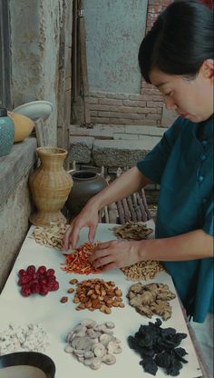 a woman standing in front of a table filled with nuts and other food items on top of it