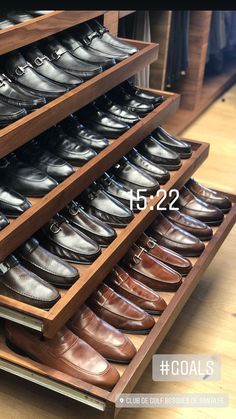 a wooden shoe rack filled with lots of men's shoes on top of a hard wood floor