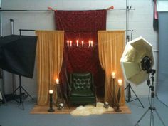 a chair in front of a backdrop with candles and lights on the floor next to it