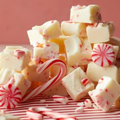 a pile of white and red candy canes on top of a striped table cloth